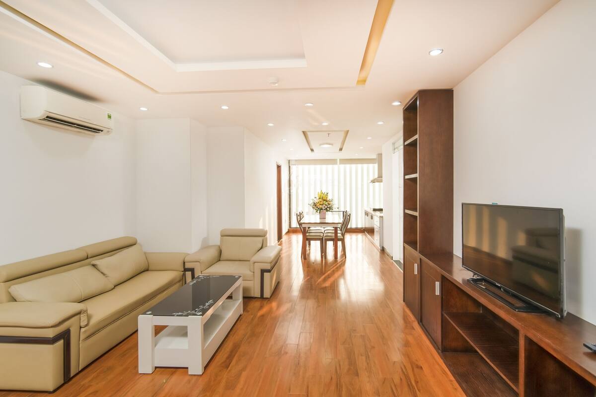 A modern living room with a sofa, coffee table, TV stand, and wooden flooring.