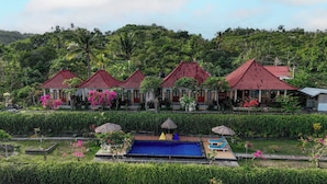 Un complexe hôtelier comprenant plusieurs villas aux toits rouges, une piscine et une végétation luxuriante.