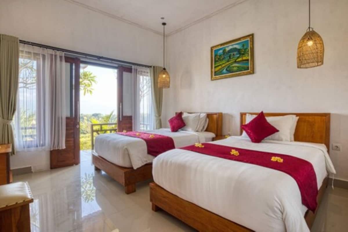 A hotel room with two beds, a painting on the wall, and a view through the window.