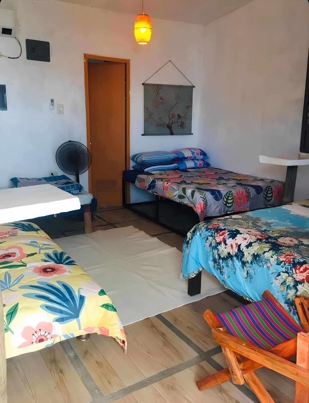Een kamer met twee bedden, een houten stoel, een ventilator en een deur.