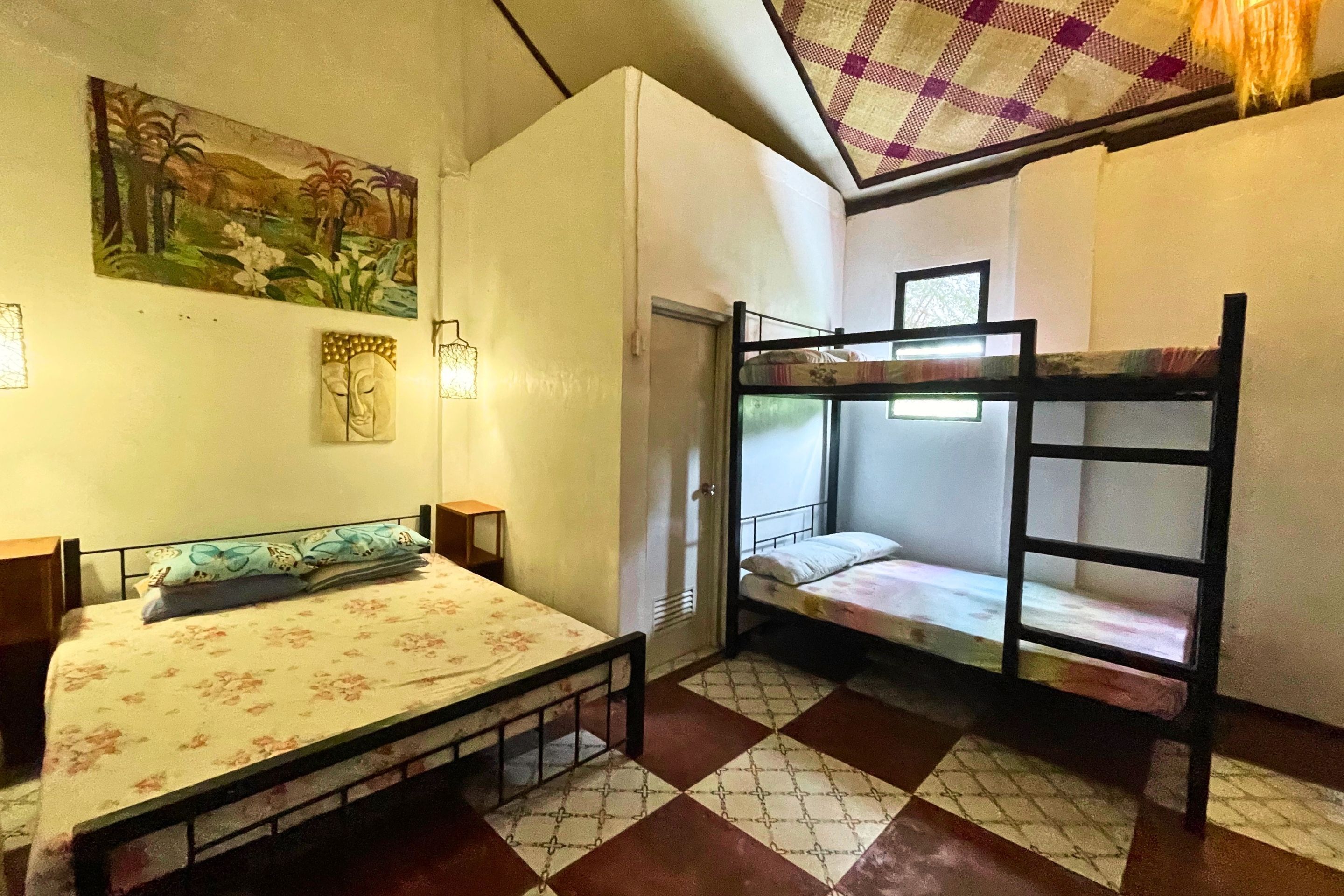 A room with a bed, a bunk bed, a painting, and a patterned floor.