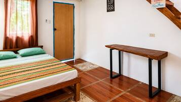 A bedroom with a bed, a bench, a door, and a wall sign.