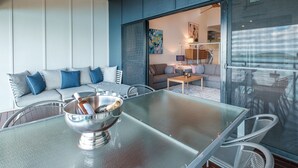 Ein modernes Wohnzimmer mit einem Glastisch, einer blauen Couch und einem großen Fenster.