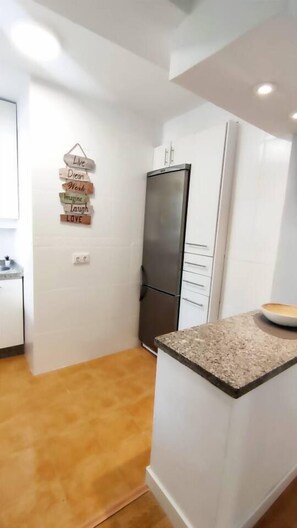 A kitchen with white cabinets, a granite countertop, and a refrigerator. - Yaye House, Fuengirola (Fuengirola)