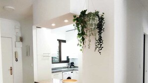 Una cocina moderna con armarios blancos, encimera de madera y una planta colgante.