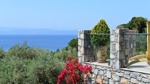 Un muro de piedra con una planta en maceta y un banco de madera con vistas a un paisaje.