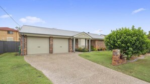A single-story house with a garage, a front yard, and a small garden area.