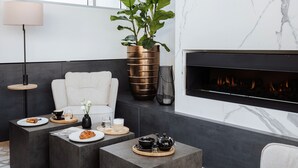 A modern living room with a fireplace, a sofa, and a coffee table with a teapot and cup. - Hotel Slatina (Rogaska Slatina)