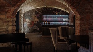 A dimly lit room with a brick archway, a piano, and a bar area with shelves and glasses. - Hotel Slatina (Rogaska Slatina)