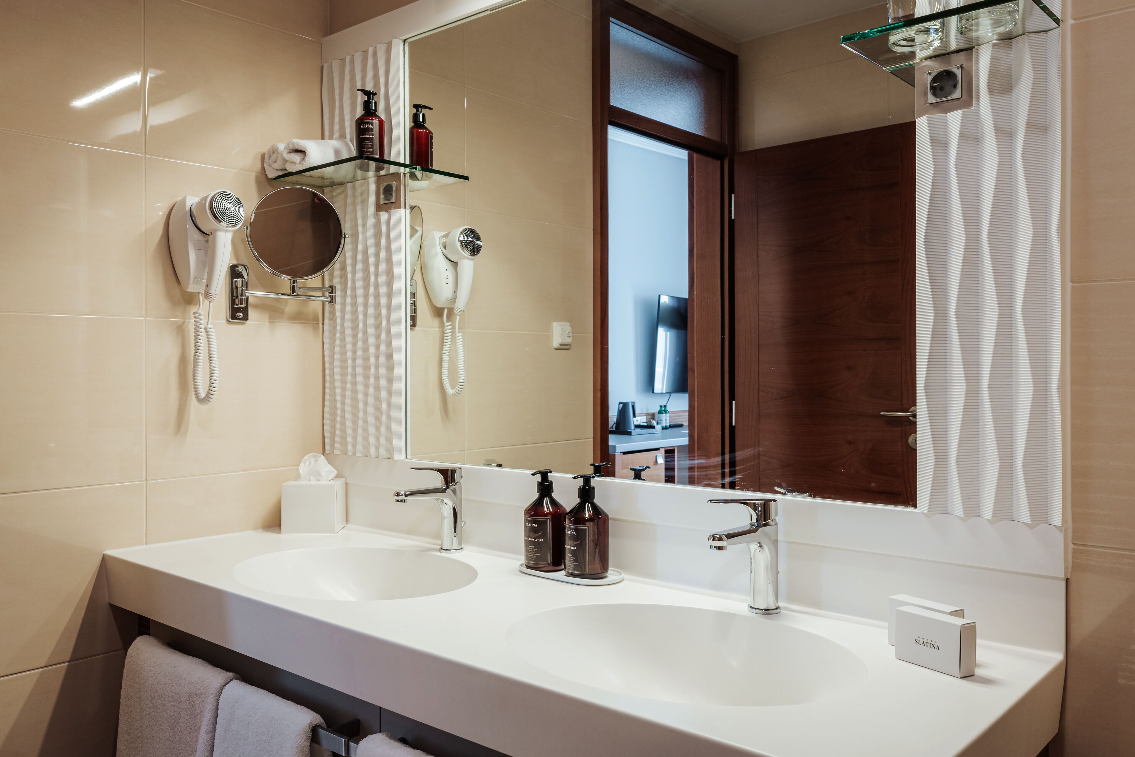 Un baño moderno con dos lavamanos, un espejo grande y un secador de pelo en la pared.