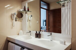 Un baño moderno con dos lavamanos, un espejo grande y un secador de pelo en la pared.