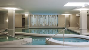 A modern indoor swimming pool with multiple lanes, a central viewing area, and a decorative light wall. - Hotel Slatina (Rogaska Slatina)