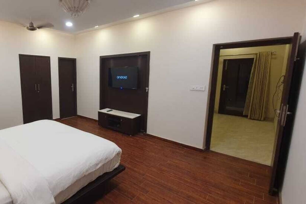 Un dormitorio con cama, televisor, armario y puerta que da a otra habitación.