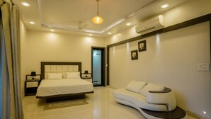 Un dormitorio moderno con cama, mesitas de noche, sofá y ventilador de techo.