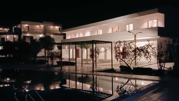 Un hotel moderno con un área exterior cubierta y una piscina.