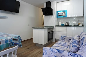 Uma cozinha compacta com micro-ondas, forno e televisão na parede.