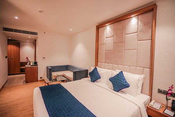 A hotel room with a large bed, a desk, and a seating area.