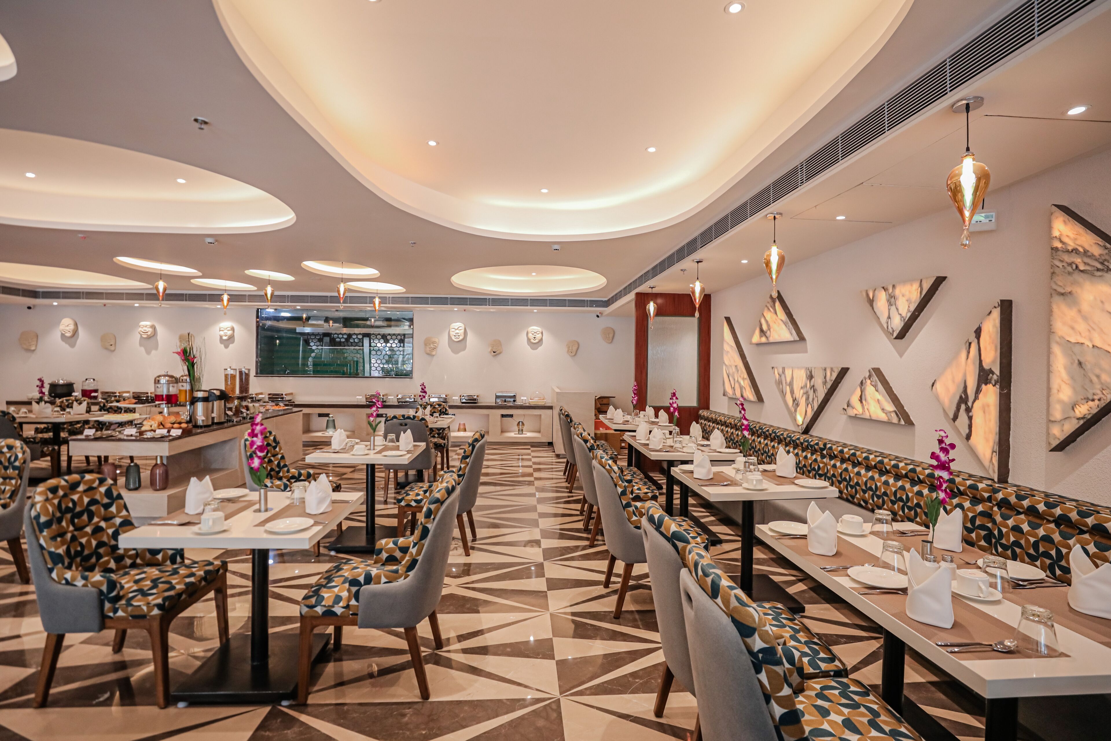 Un espace de restauration moderne avec de longues tables, des chaises aux motifs originaux et un motif géométrique sur le sol.