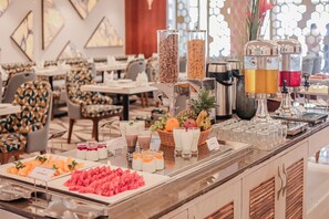 A buffet area with various food items and beverages, including fruits, yogurt, and juices.
