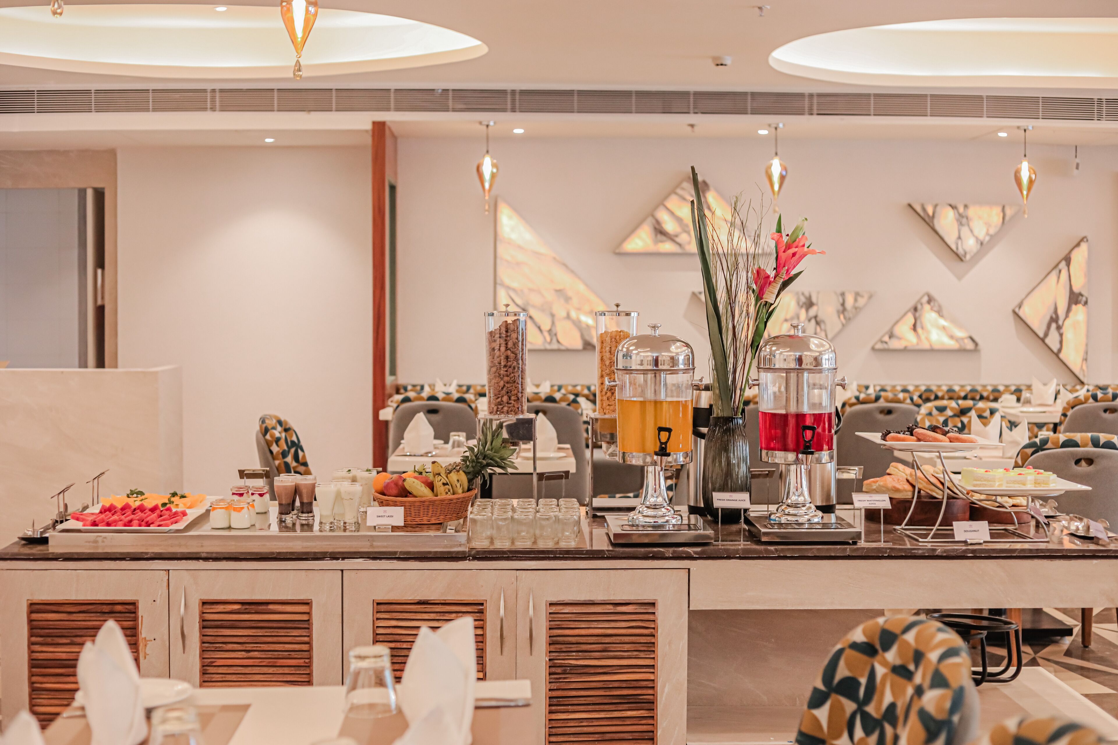 A buffet setup with various food items and beverages, including a fruit platter, sandwiches, and a coffee machine.