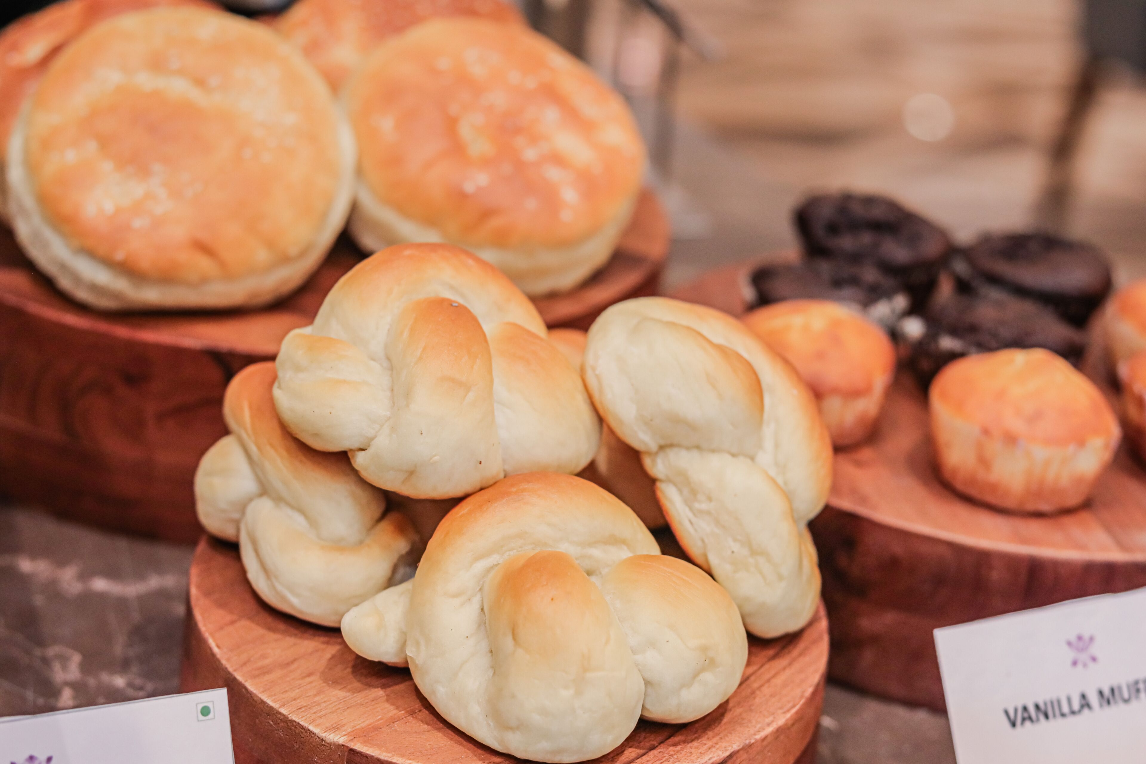 Une variété de produits de boulangerie, notamment des petits pains et des muffins, présentés sur des planches en bois.