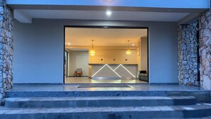 Eine moderne Hotelhalle mit Steinwand, einer Rezeption und einer Treppe, die in die oberen Stockwerke führt.