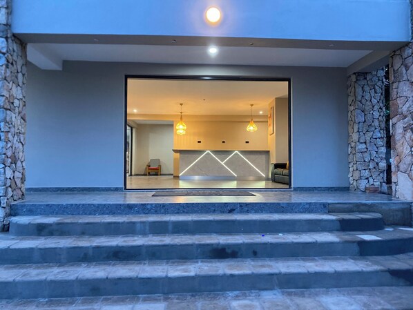A modern hotel lobby with a stone wall, a reception desk, and a staircase leading to the upper floor. - The Outlook At Victoria Falls (Victoria Falls)