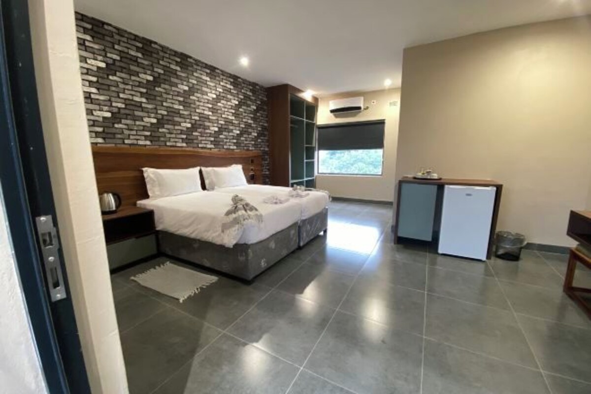 A bedroom with a bed, a desk, a wardrobe, and a window.