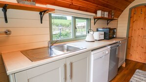 Een keuken met een spoelbak, witte kastjes, een broodrooster en een waterkoker.