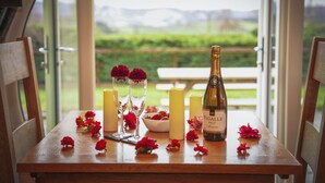 Een tafel met een fles wijn, kaarsen en rode bloemen.
