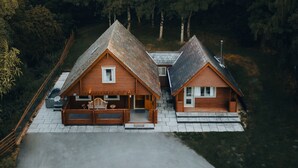 Une cabane en bois avec un toit en pente, une véranda avec des sièges et une petite terrasse.