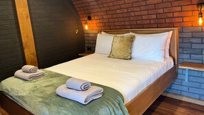 A hotel room with a brick ceiling, a wooden bed frame, and a green blanket. - Otters View -  Underground Hobbit Home Sleeping 6 guests, Pet Friendly (Rhayader)