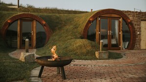A circular building with a fire pit in the foreground. - Otters View -  Underground Hobbit Home Sleeping 6 guests, Pet Friendly (Rhayader)