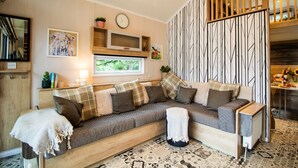 Een gezellige woonkamer met een houten bank, een klok en een raam met uitzicht op groen.
