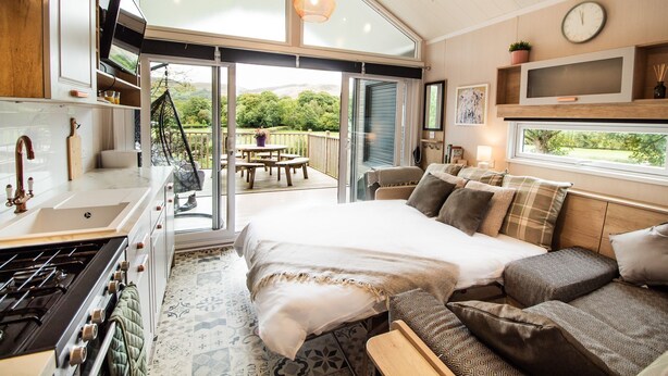 Een moderne slaapkamer met een groot bed, een bank, een eethoek en een keuken.
