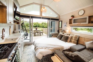 Une chambre moderne avec un grand lit, un canapé, un coin repas et une cuisine.