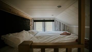 A bedroom with a bed, a window, and a wooden headboard.