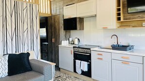 A modern kitchen with white cabinets, a black stove, and a wooden ceiling.