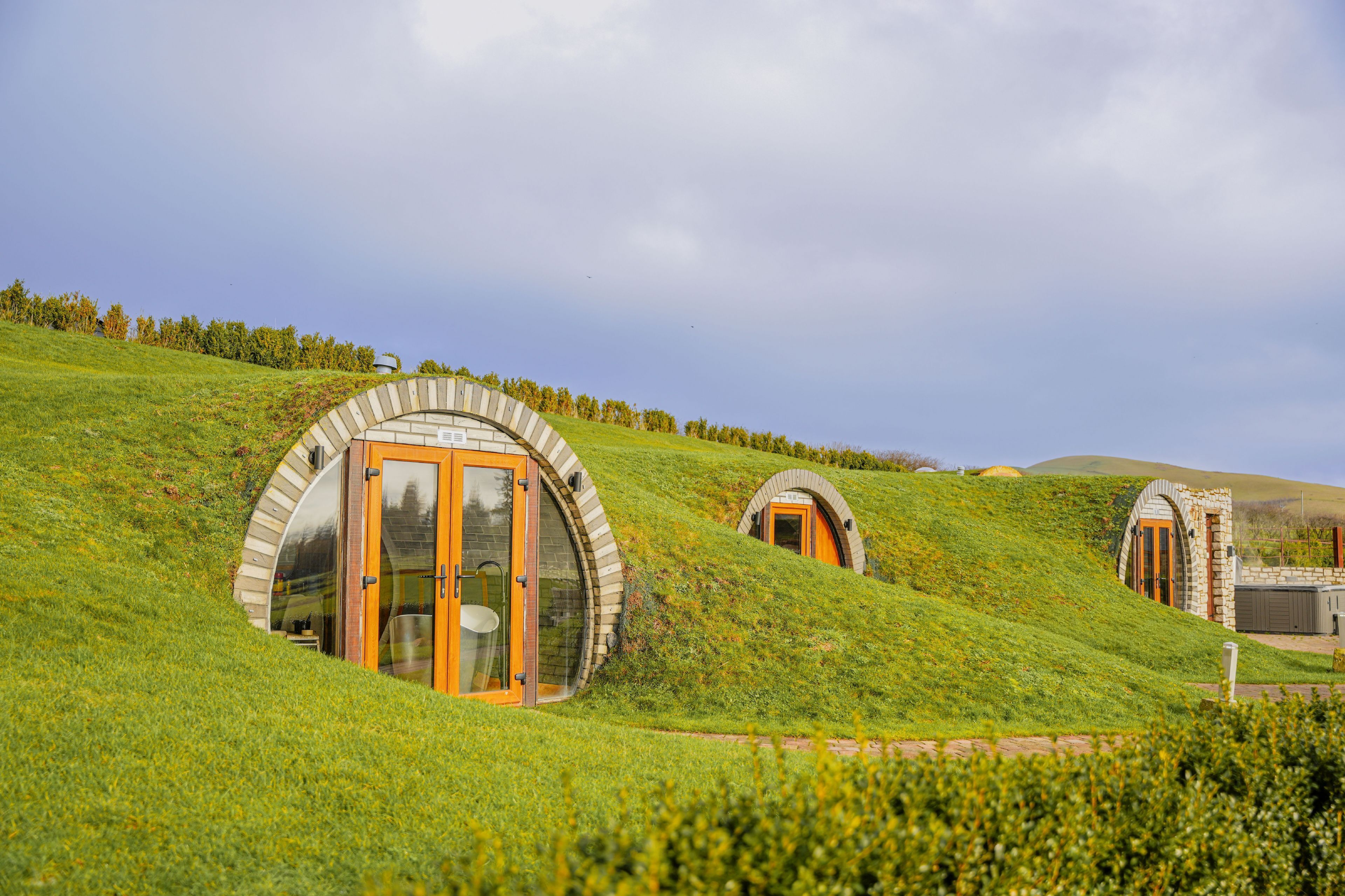 Three dome-shaped buildings nestled on a grassy hillside.