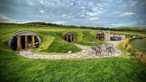 Un bâtiment circulaire doté d’une porte et d’un patio aménagé avec du mobilier d’extérieur.