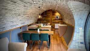 Une cuisine chaleureuse, aménagée dans un style mansardé, avec des murs en briques apparentes, un plancher en bois et un îlot central doté de sièges.