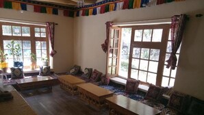 A traditional room with a sofa set, wooden tables, and a window with curtains.