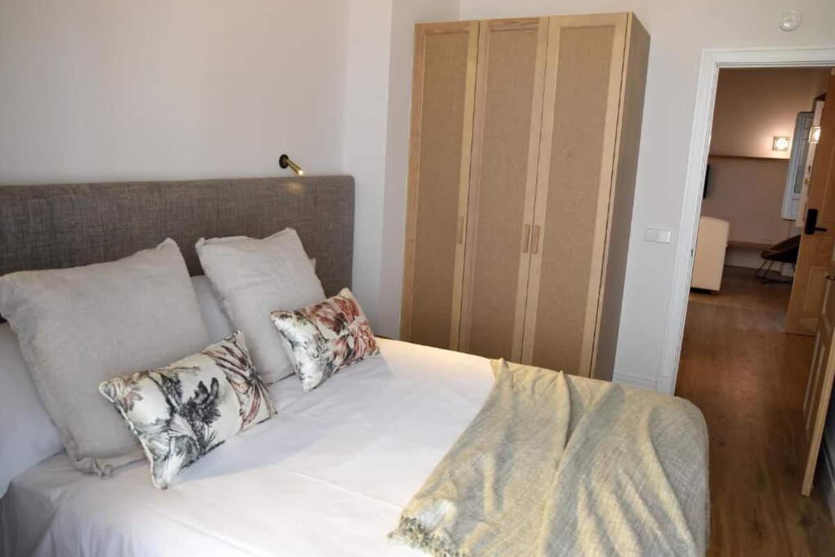 A bedroom with a bed, pillows, a bedside lamp, and a wardrobe.