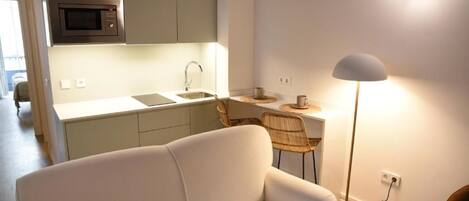 Een moderne keuken met een magnetron, spoelbak en een eethoek.
