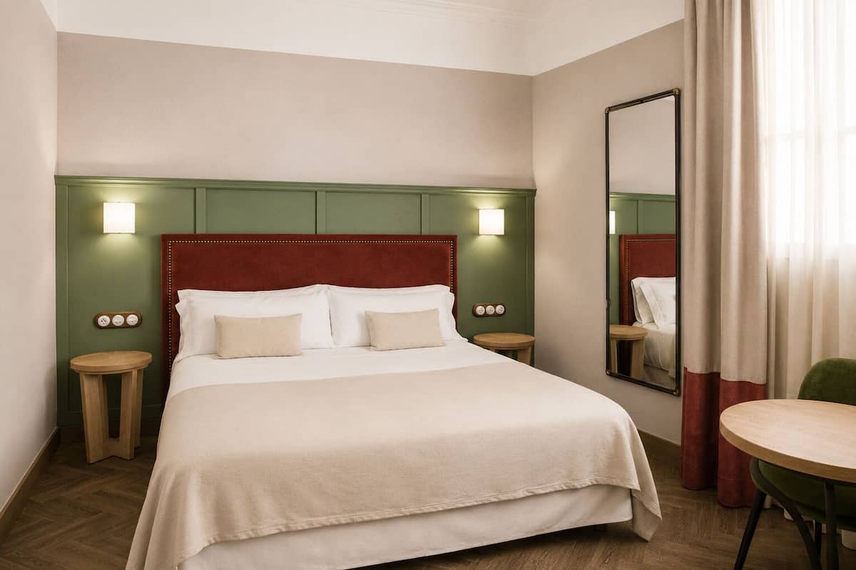 A hotel room with a bed, bedside tables, a mirror, and a chair.