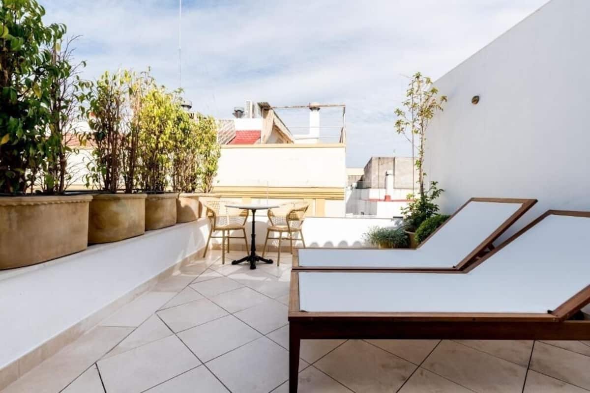 A rooftop terrace with a lounge area, a table, and chairs.
