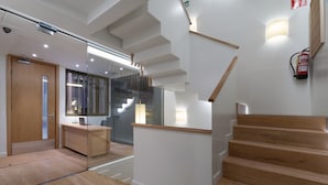 A modern interior with a wooden staircase, a reception desk, and a glass partition. - Casa Bella Gracia by Aspasios (Barcelona)