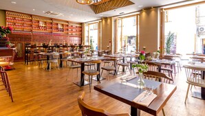 A spacious restaurant with wooden flooring, multiple tables and chairs, and a wall of red bottles. - Sirius Luxury Rooms (Split)