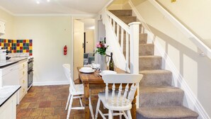 A kitchen with a dining table, chairs, and a staircase. - Sunny Beck Cottage - cosy cottage in Mundesley (Mundesley)
