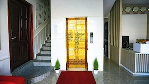 A hotel lobby with a reception desk, a staircase, and a patterned door. - TTR Vincent Hotel (Xuan Huong - Da Lat)